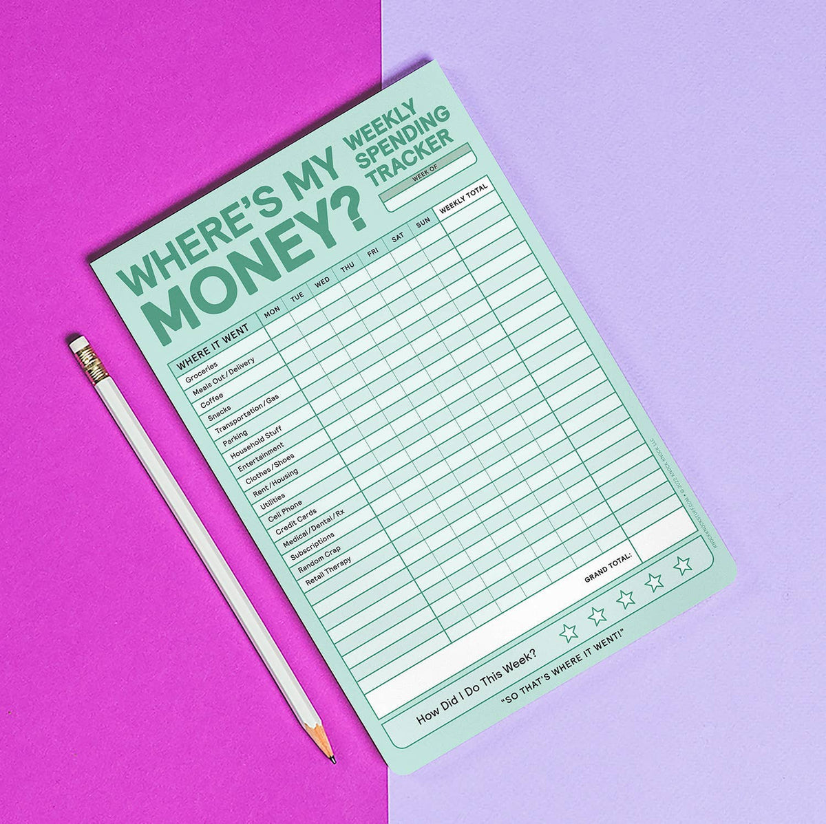 Where's My Money? Weekly Spending Tracker notepad lying at an angle beside a white pencil on a split purple and lavender background — showing full mint green grid layout with bold title and star rating footer