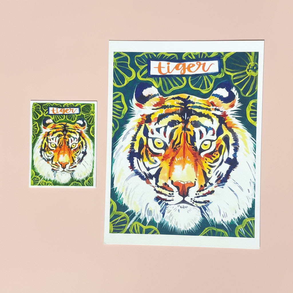 Made by Shellie Tiger vinyl sticker — front view showing print detail of bold watercolor tiger face with orange and black stripes, golden eyes, and "tiger" hand-lettered in blue banner; white border; unpackaged
