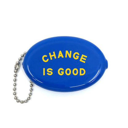 Three Potato Four Change Is Good rubber coin pouch on white background — oval glossy cobalt blue squeeze pouch with bold yellow arched "CHANGE IS GOOD" lettering across the face in two lines; silver ball chain with lobster clasp attached at left side