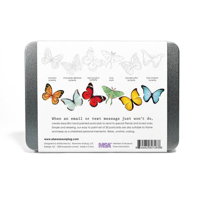 Back of Elseware Unplug coloring postcards tin on white background — silver tin with white label; top row shows 6 lightly printed uncolored butterfly outlines; bottom row shows 6 fully colored butterfly and moth illustrations labeled Monarch Butterfly, Chocolate Albatross Butterfly, Red Monarch Butterfly, Luna Moth, Clouded Sulfur Butterfly, and Blue Morpho Butterfly; tagline reads "When an email or text message just won't do, create beautiful hand painted postcards to send to special friends and loved ones