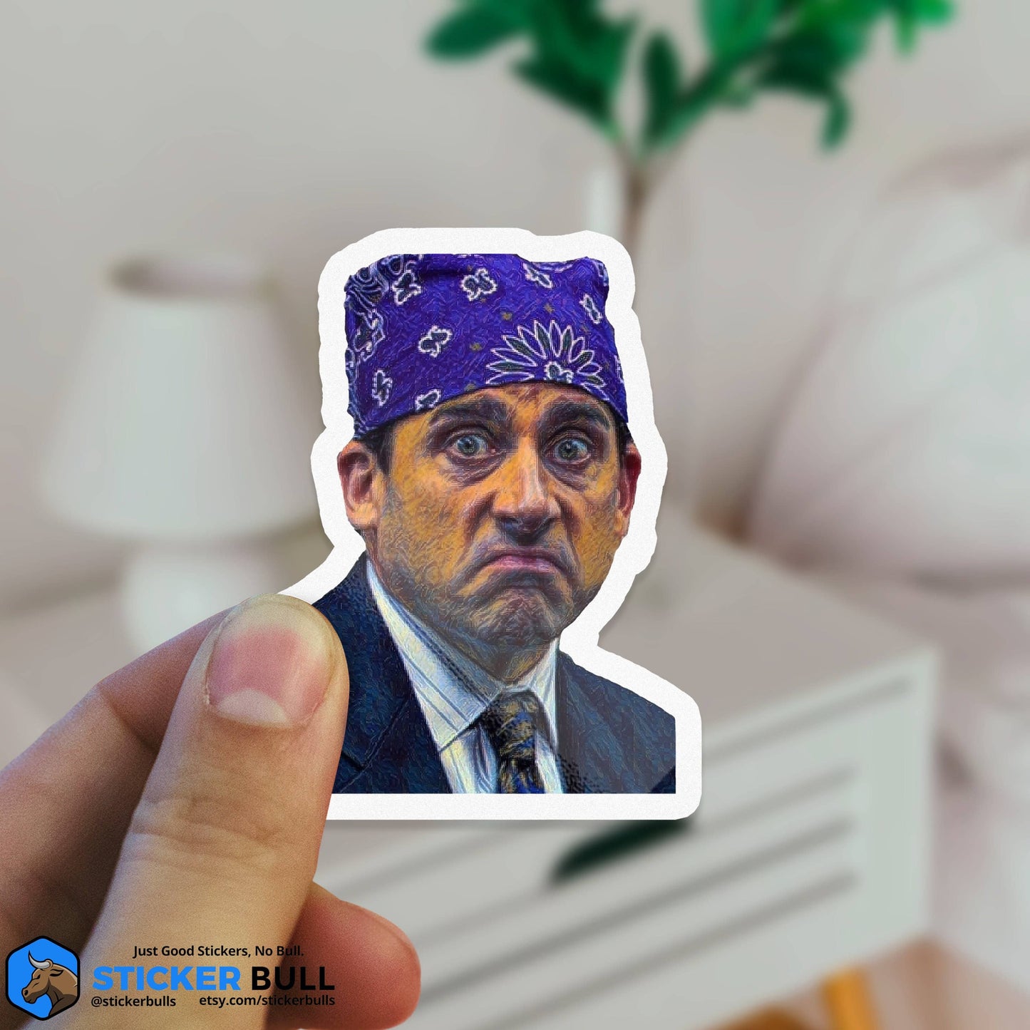 Hand holding a Sticker Bull Prison Mike The Office die cut vinyl sticker against a blurred living room background — illustrated Michael Scott as Prison Mike in purple bandana; white die cut border; Sticker Bull logo in corner