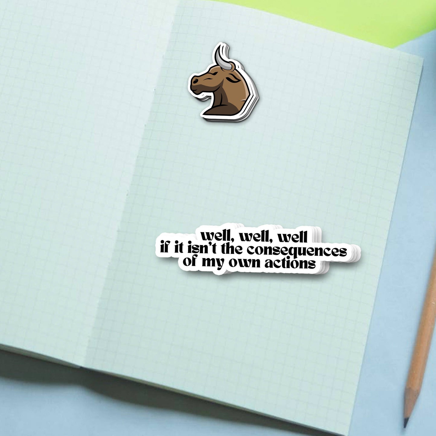 Sticker Bull Well Well Well If It Isn't the Consequences of My Own Actions funny vinyl sticker and Sticker Bull bull logo sticker applied to an open notebook against a light blue and green background with a pencil