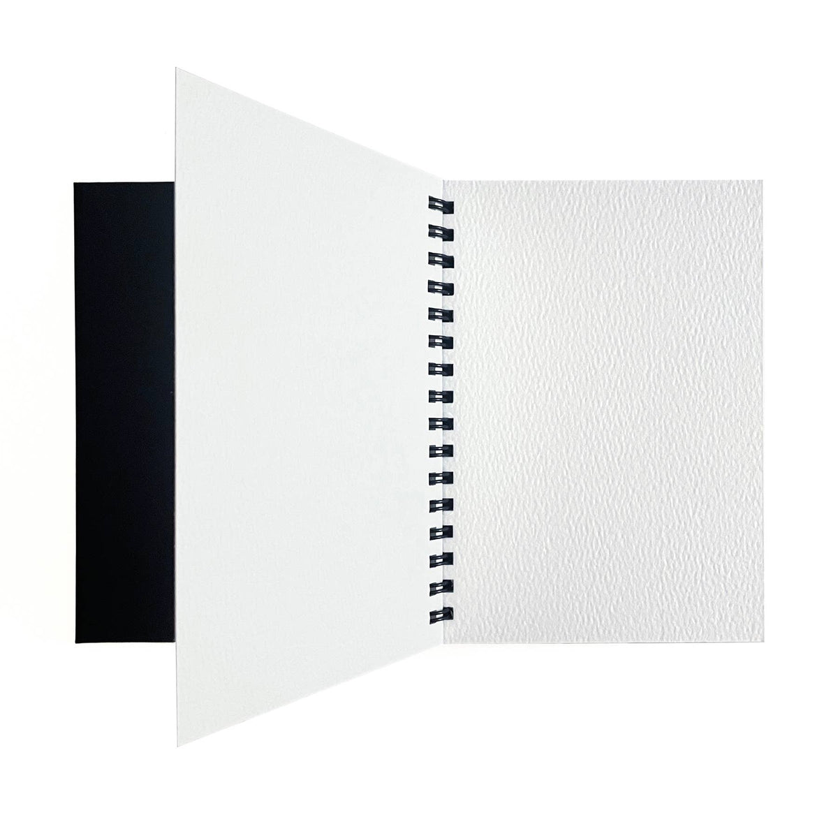 Elseware Unplug watercolor paper pad open flat on white background — black cover folded to the left; right side shows a blank white cold press watercolor paper page with visible cotton rag texture; black spiral binding visible in center