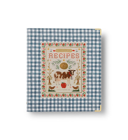 Rifle Paper Co. Home Sweet Home Recipe Binder front cover; blue gingham hardcover with gold corner accents; illustrated Recipes label featuring a cow, chickens, wheat sheaves, and florals; white background