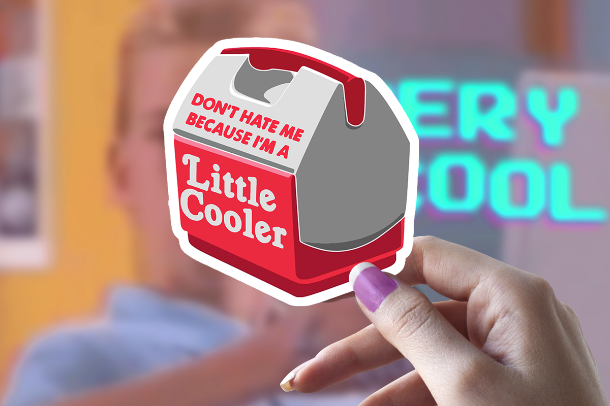 Hand holding a Sticker Bull Don't Hate Me Because I'm A Little Cooler die cut vinyl sticker in front of a blurred neon sign background reading "Very Cool" — illustrated red and gray mini cooler with red and white pun text; white die cut border; purple manicured nails

