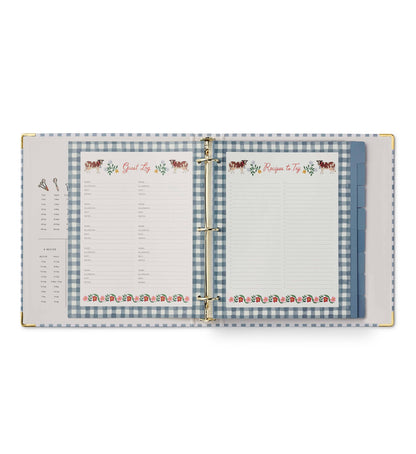Rifle Paper Co. Home Sweet Home Recipe Binder open to Guest Log fill-in page on left and Recipes to Try fill-in page on right; both pages feature illustrated cow and floral borders with blue gingham binder background