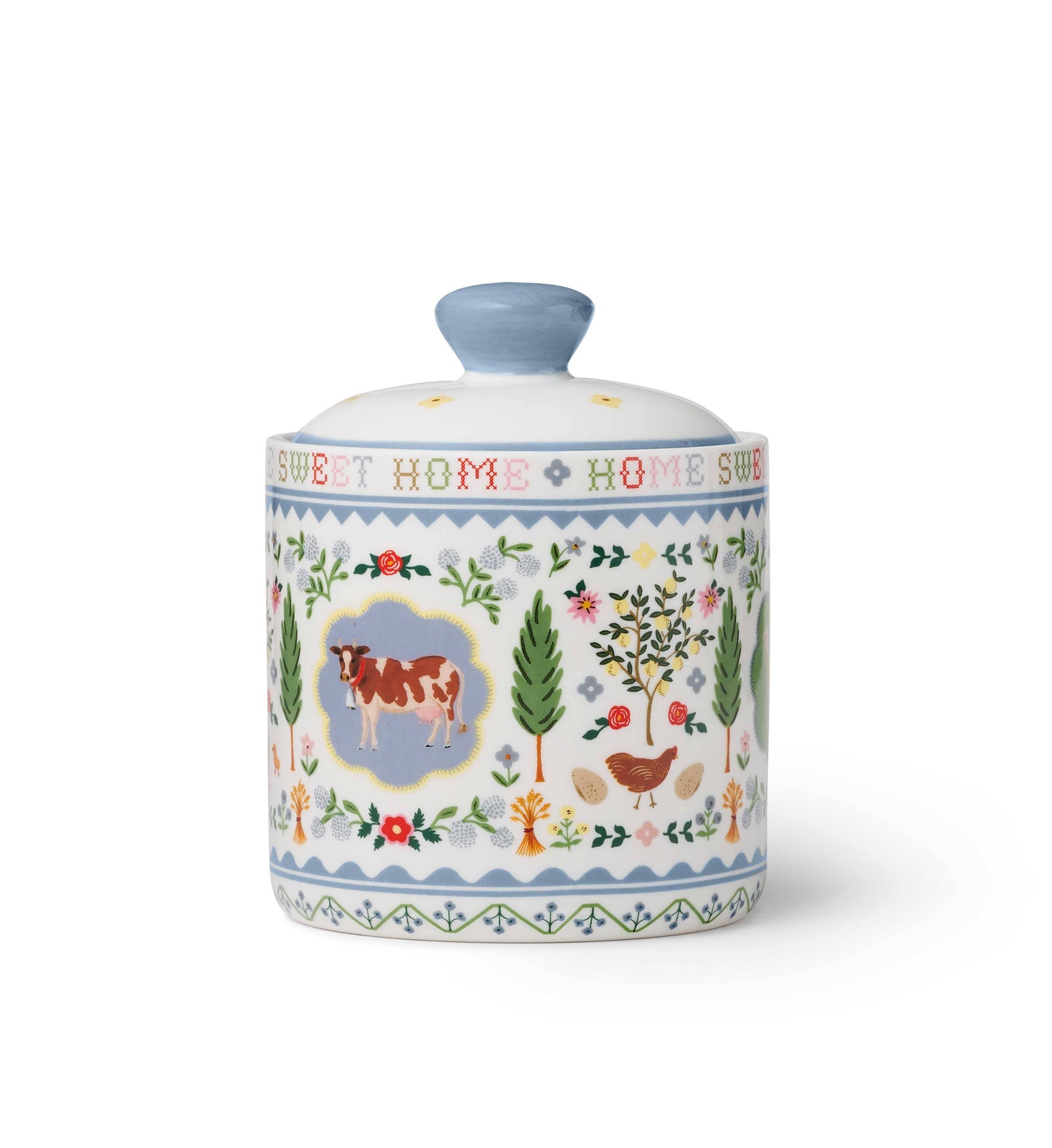 Rifle Paper Co. Home Sweet Home Porcelain Canister — back view — reverse side showing a brown and white cow in a blue scalloped medallion at center, a hen with eggs, fruit trees, cypress trees, roses, and wildflowers; "SWEET HOME" cross-stitch lettering visible around neck; soft blue zigzag border bands; white background