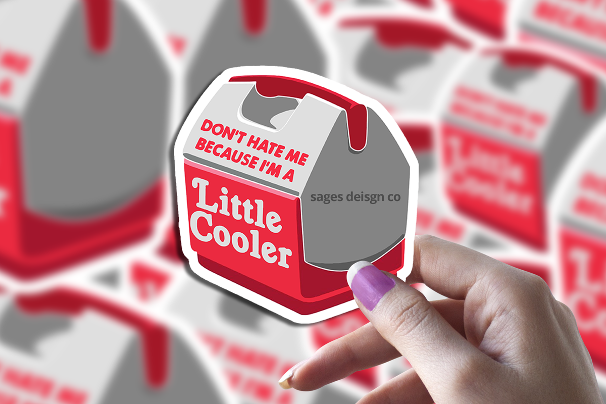 Hand holding a Sticker Bull Don't Hate Me Because I'm A Little Cooler die cut vinyl sticker in front of a blurred background of the same sticker repeated — illustrated red and gray mini cooler with red and white pun text; white die cut border; purple manicured nails