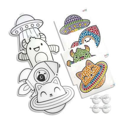 Flat lay of all OOLY Sun Sparkles Cosmic Fun kit contents on white background: 4 blank translucent suncatcher shapes (UFO, alien, rocket, space cat), 3 color guide cards (UFO, alien, space cat), and 4 clear suction cup hooks