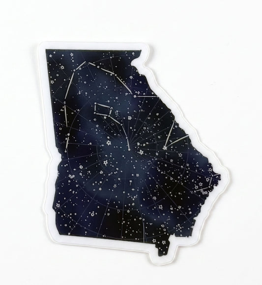 Made by Shellie Georgia Constellations vinyl sticker — Georgia state silhouette filled with a deep navy night sky, scattered stars, and constellation lines mapped across the state shape; die-cut with white border; white background