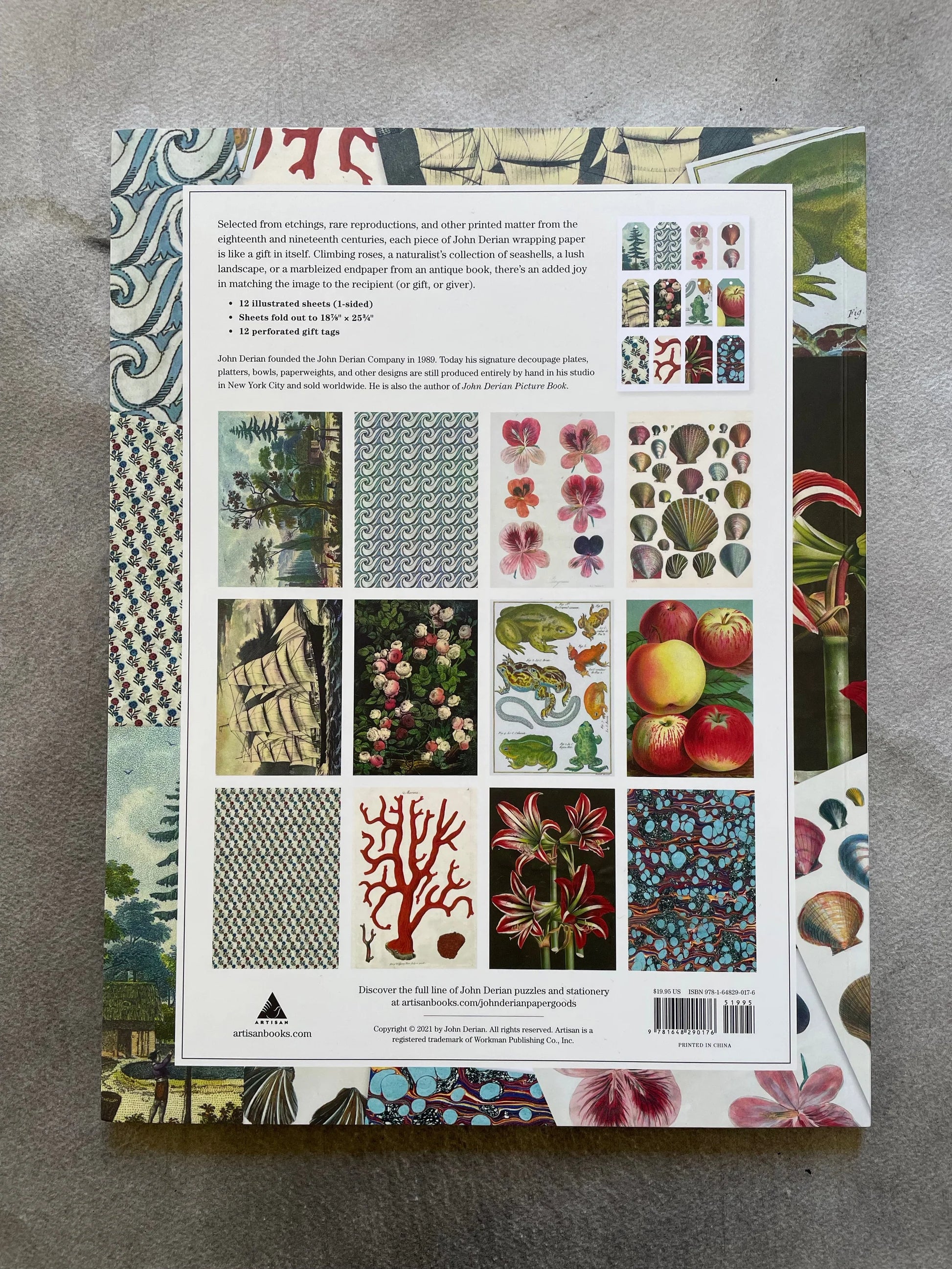 Back cover of John Derian Wrapping Paper & Gift Tags — white background with descriptive text, bullet points listing 12 illustrated sheets, fold-out size 18⅞"×25¾", and 12 perforated gift tags, plus a grid of all 12 wrapping paper sheet thumbnails including landscape, roses, geraniums, seashells, frogs, apples, crosshatch, red coral, red amaryllis, marbled paper, and small floral designs, with Artisan Books logo and ISBN barcode