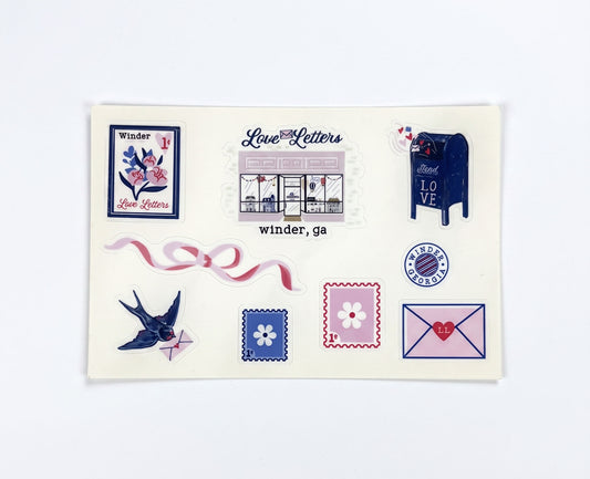 Made by Shellie Love Letters Sticker Sheet — illustrated stickers including Love Letters storefront with "winder, ga" label, floral postage stamp, navy "Send LOVE" mailbox, pink ribbon bow, swallow with envelope, flower stamps, Winder Georgia postal seal, and pink LL heart envelope; cream sticker sheet; white background