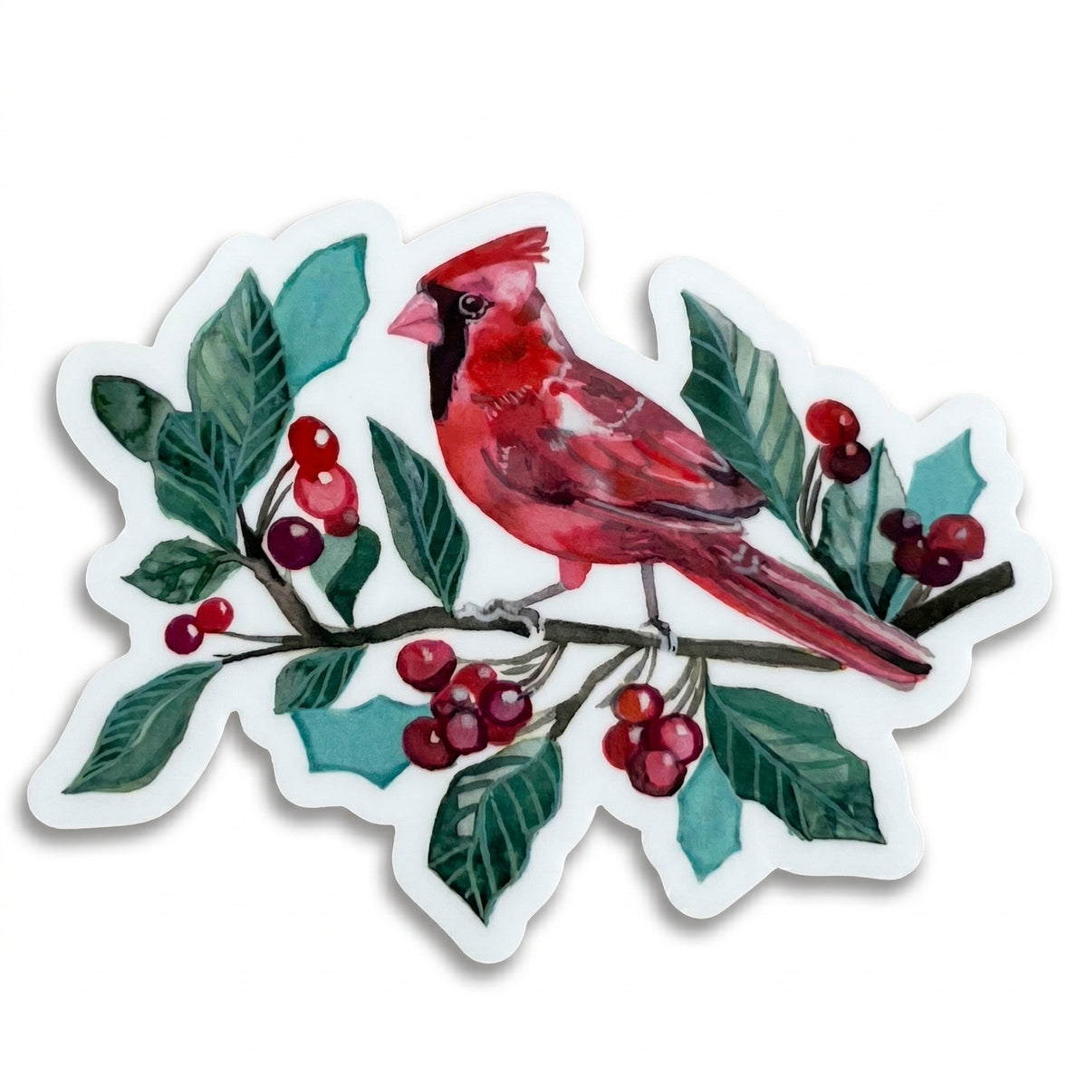 Made by Shellie Cardinal in Berries vinyl sticker — vivid watercolor male cardinal perched on a branch with deep green holly leaves, clusters of red berries, and teal accents; die-cut with white border; white background
