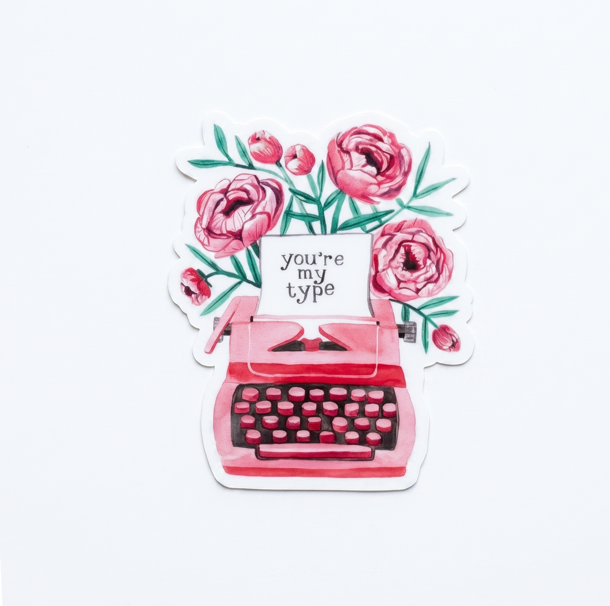 Made by Shellie You're My Type vinyl sticker — pink watercolor vintage typewriter with "you're my type" typed on paper, overflowing with lush pink peonies and teal green leaves; die-cut with white border; white background