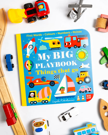 Flat lay of My BIG Playbook: Things That Go board book cover surrounded by colorful toy vehicles including wooden trains, die-cast cars, a toy helicopter, and wooden blocks on a white background
