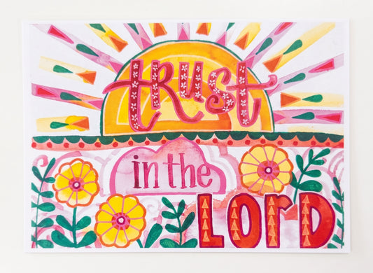 Made by Shellie Trust in the Lord Art Print — horizontal flat lay of vibrant folk-art watercolor featuring hand-lettered "Trust in the Lord," bold golden sunrise, radiating pink and green rays, and three yellow flowers; white background