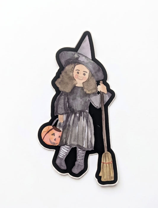 Halloween Witch Costume vinyl sticker by Made By Shellie — die-cut sticker of a watercolor little girl in a gray witch costume with tall pointy hat, holding a jack-o-lantern candy bucket in one hand and a broom in the other; black die-cut border; 2"×4"